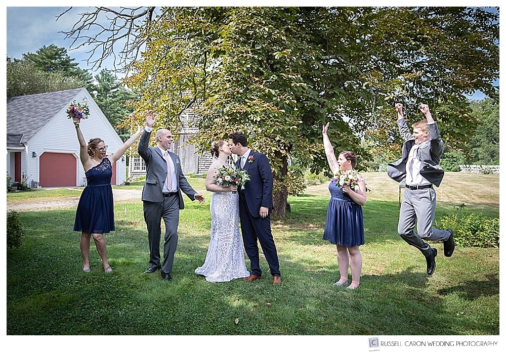 bridal party cheering while bride and groom kiss
