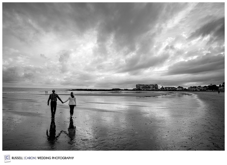 Couple walking hand in hand on a Maine beach