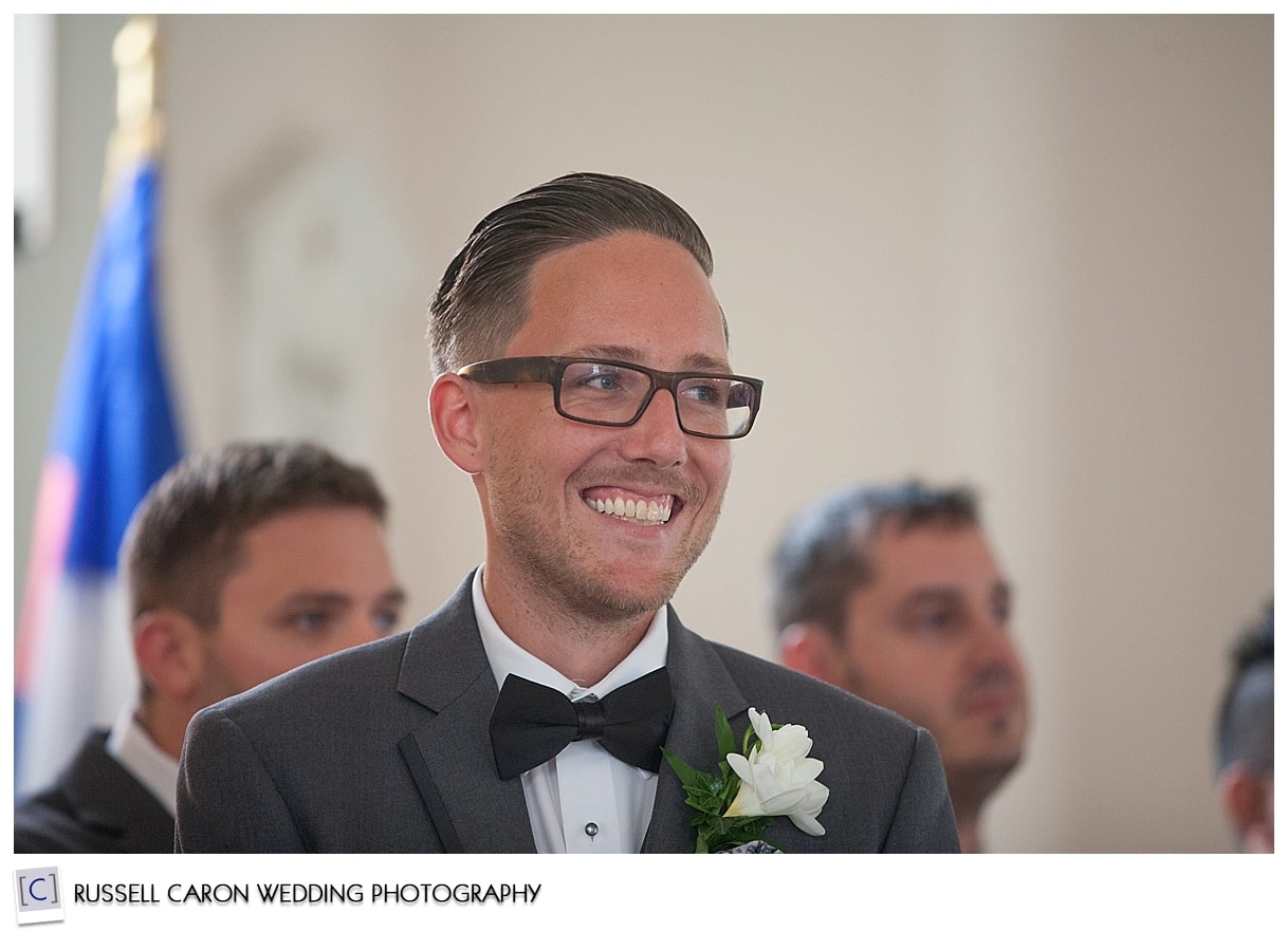 Groom watching bride walk down the aisle