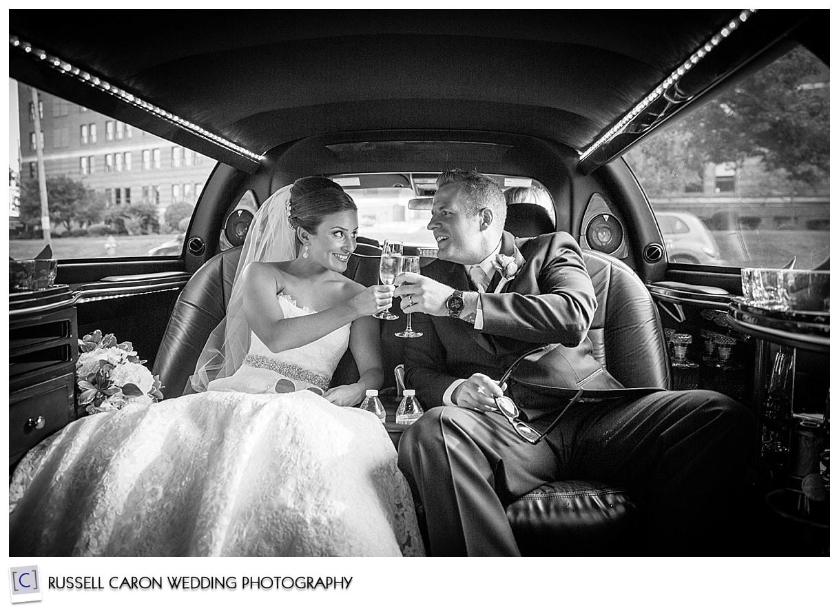 Bride and groom toast in limo