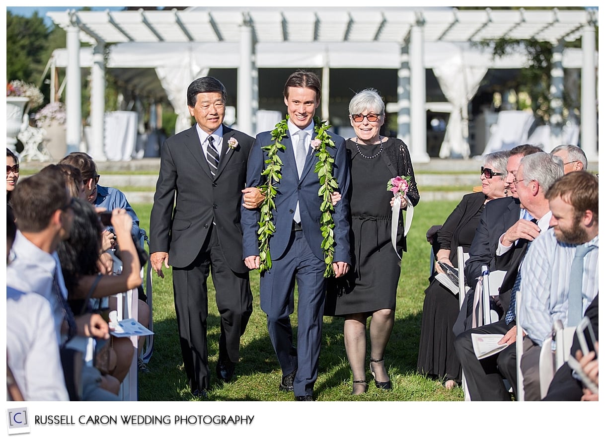 Groom walking down aisle with parents