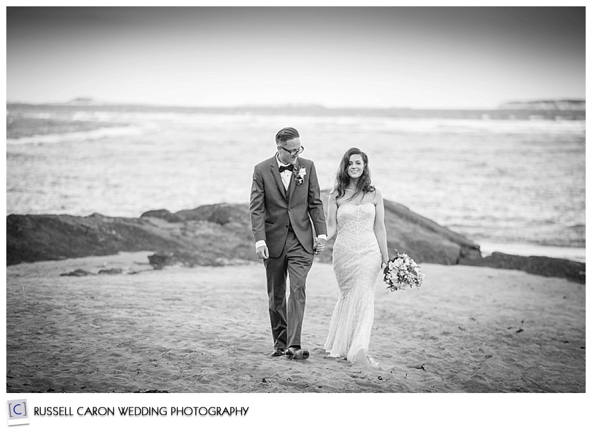 Bride and groom walking on the beach hand in hand