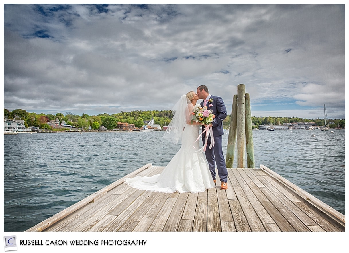 Bride and groom kissing on dock in Boothbay Maine