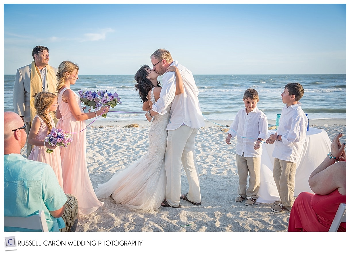 Bride and groom during first kiss, beach destination wedding