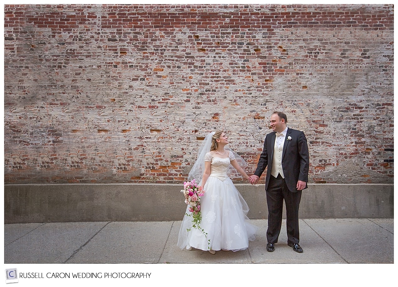 Bride and groom in front of brick wall, Exchange Street Portland Maine