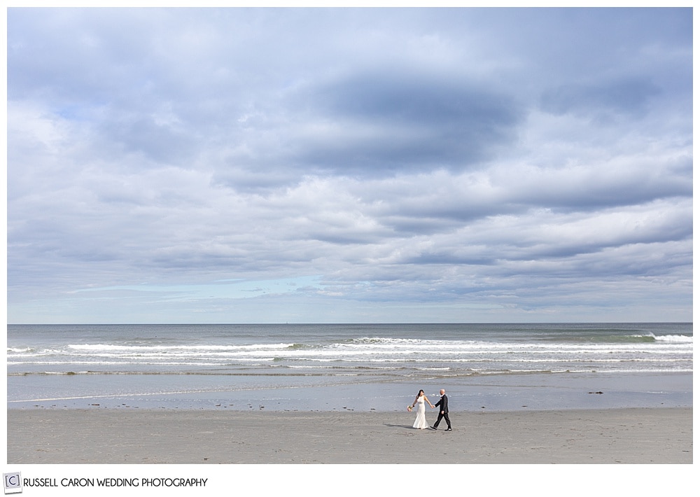 couple walks the shore at york beach maine wedding