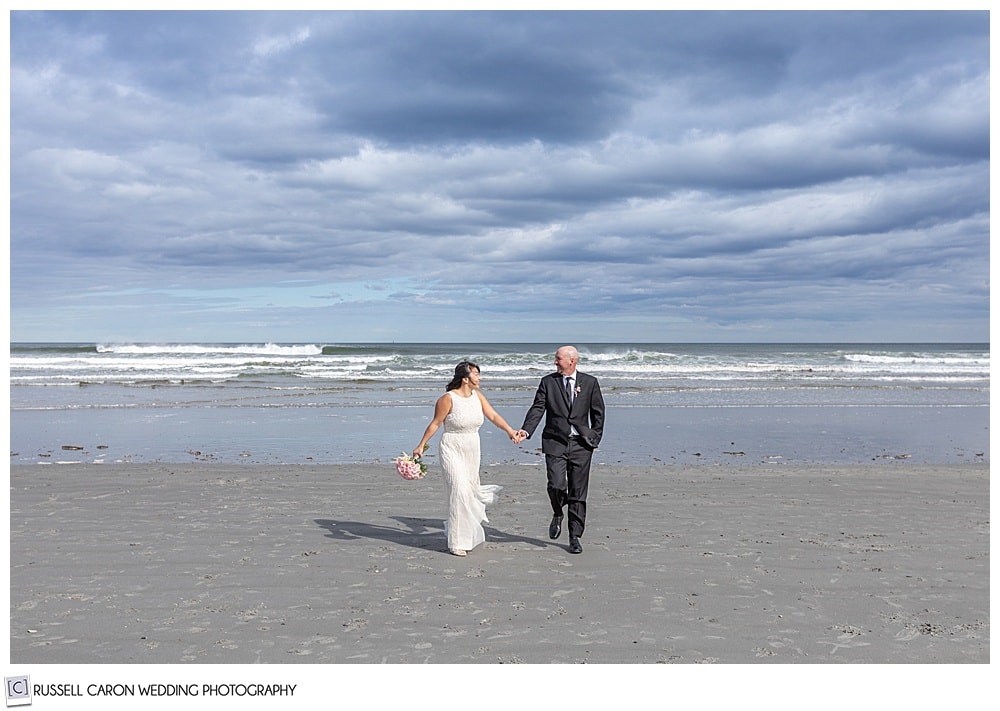 couple walks at the beach right after being married