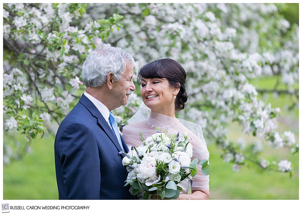 Radiant bride smiling at her groom  near an apple tree