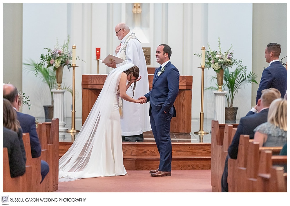 bride with her head in her hand in a funny church wedding photo at St. Martha Church, Kennebunk, Maine