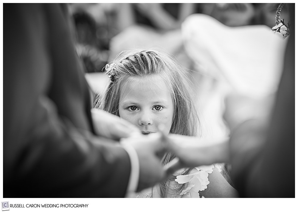 intrigued flower girl watch her father put the wedding band on her mother's finger