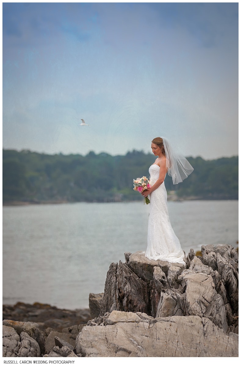 Bride on the rocks at the ocean's edge Maine