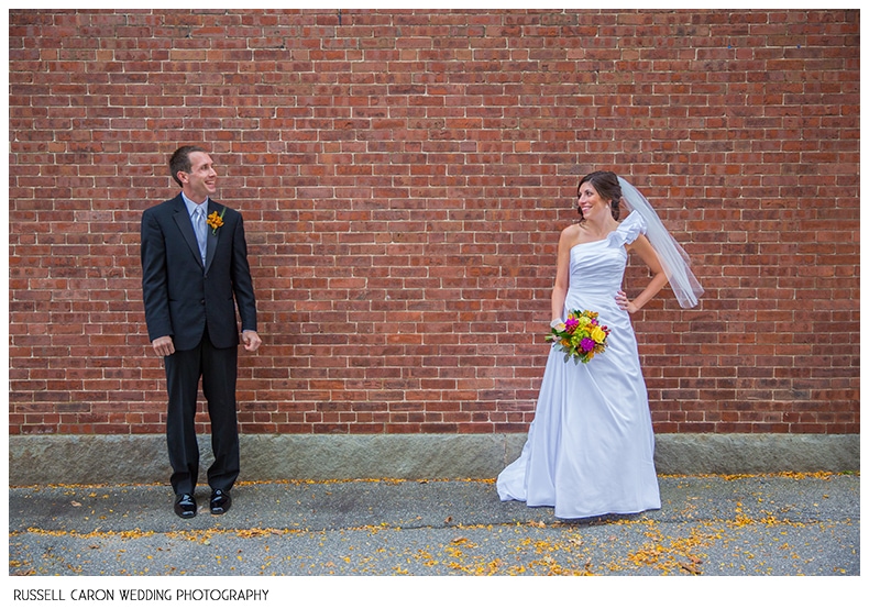 Bride and groom photographed against a brick wall