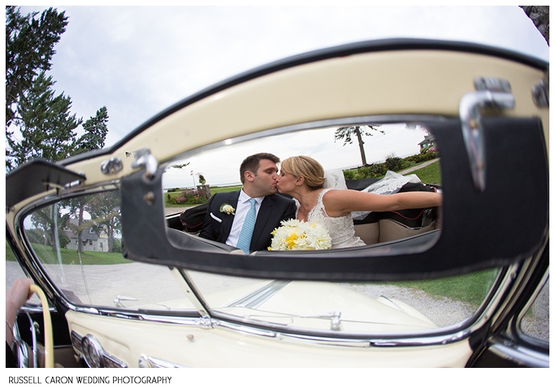 Bride and groom share a kiss in an antique bentley