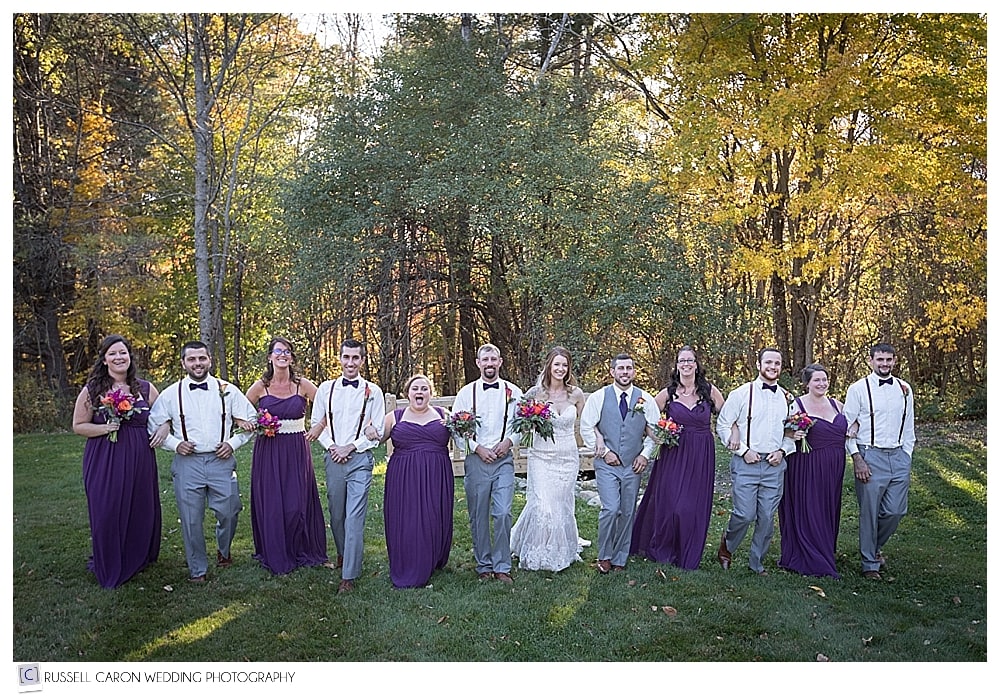 bride and groom with bridal party arm in arm