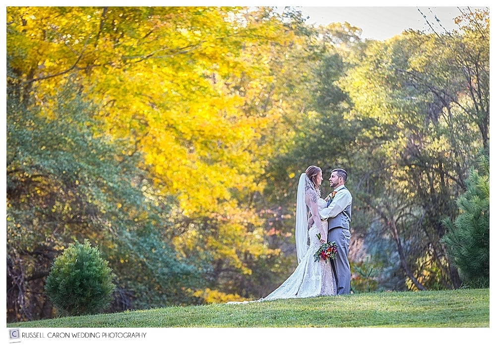 bride and groom holding each other on an autumn hillside