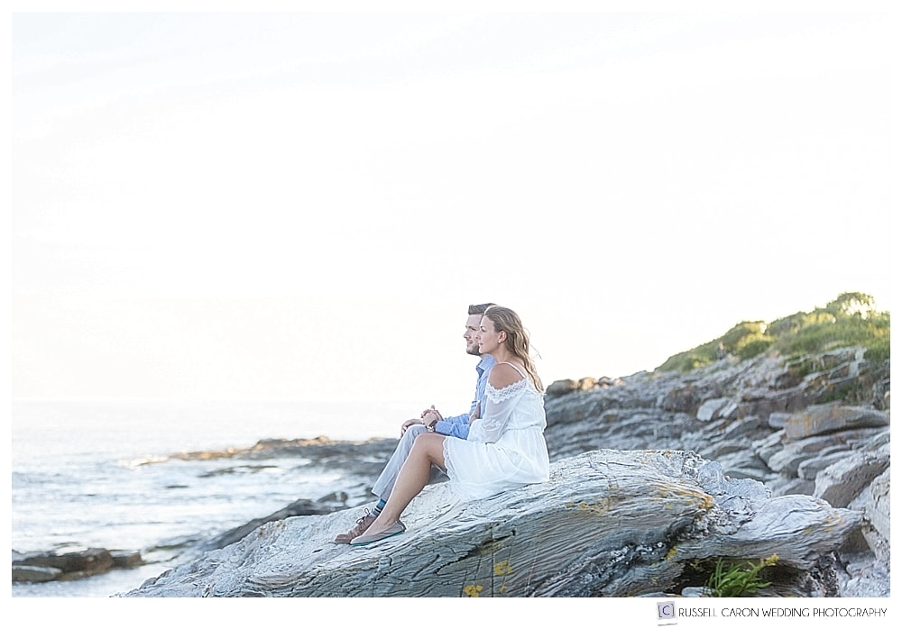man and woman sitting on rocks at the ocean's edge. A 2017 favorite Maine engagement image 