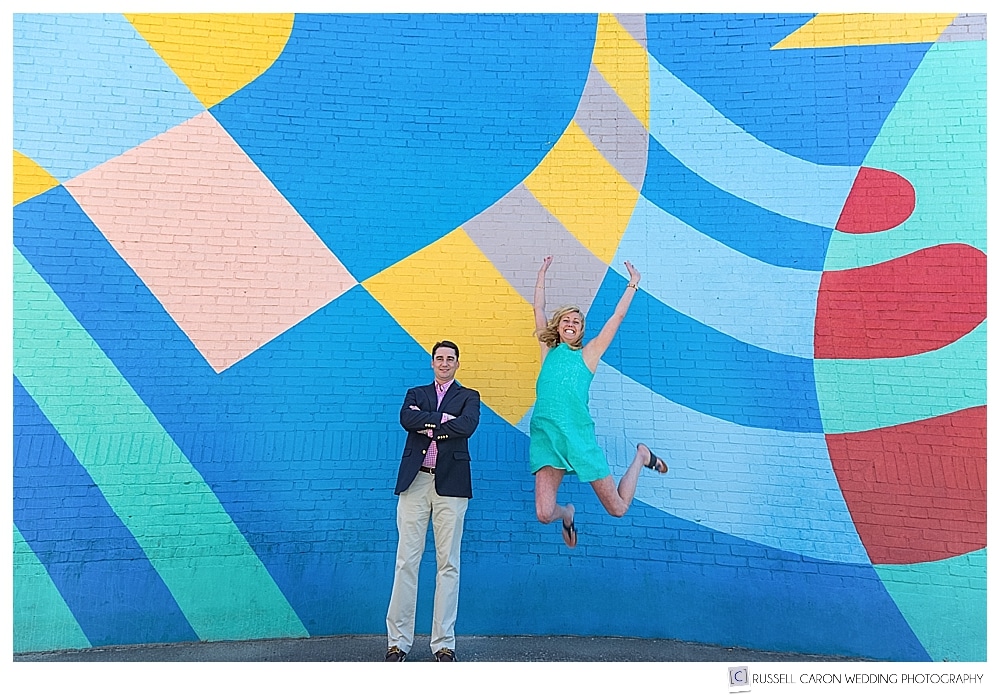 Man and woman in front of a colorful wall mural, woman is jumping in the air. 2017 Favorite Maine engagement images 