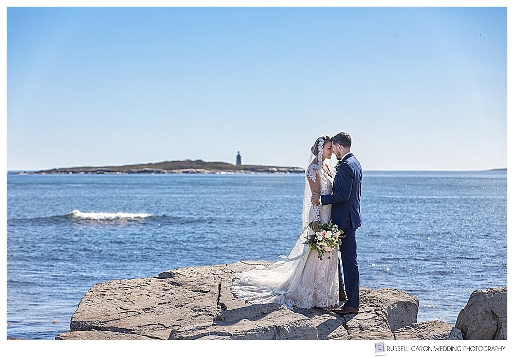 Bride and groom standing chest to chest on the coast of Maine
