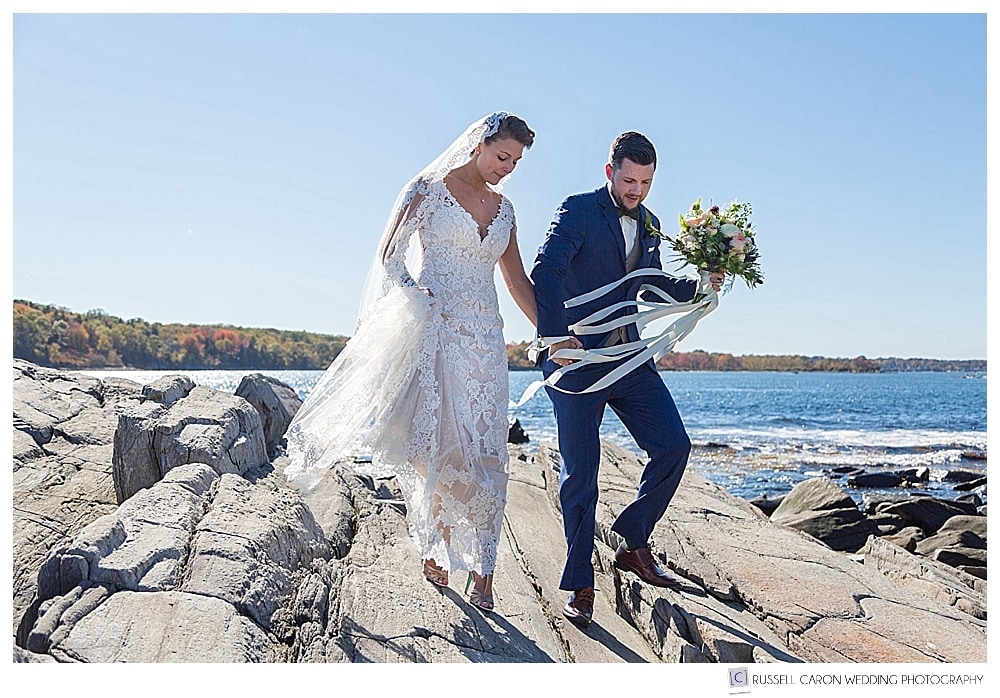 Bride and groom walking hand in hand on the granite rocks on Peaks Island Maine