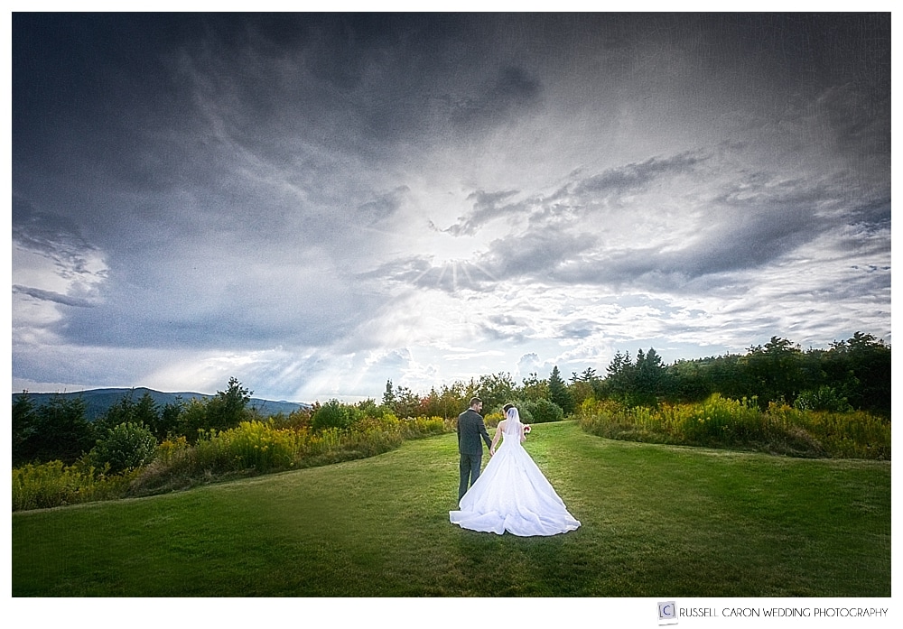 Bride and groom walking on the lawn at Point Lookout Resort, with dramatic skies. Our Maine Wedding Photography 2017 Honorable Mention 