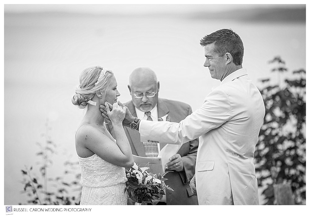 groom touches brides cheek during wedding ceremony