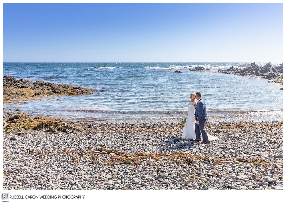 bride and groom walking on a rocky beach in Kennebunkport, Maine