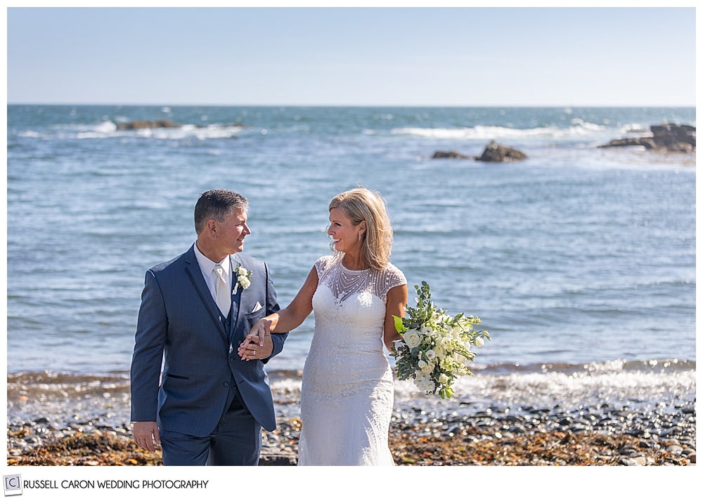 bride and groom walking and holding hands on a Kennebunkport, Maine beach