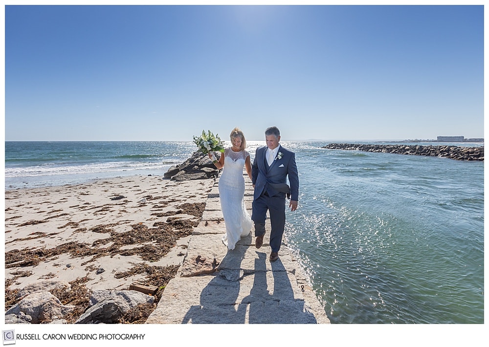 bride and groom walking toward the camera on the Kennebunkport, Maine, breakwater