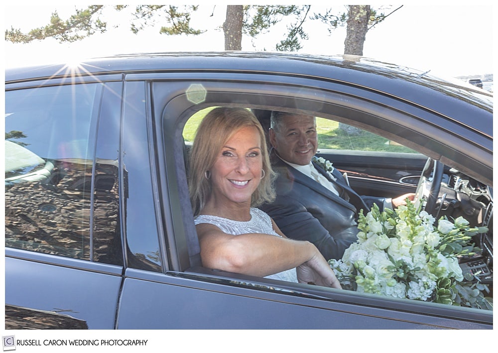 bride and groom sitting in a black car, smiling 