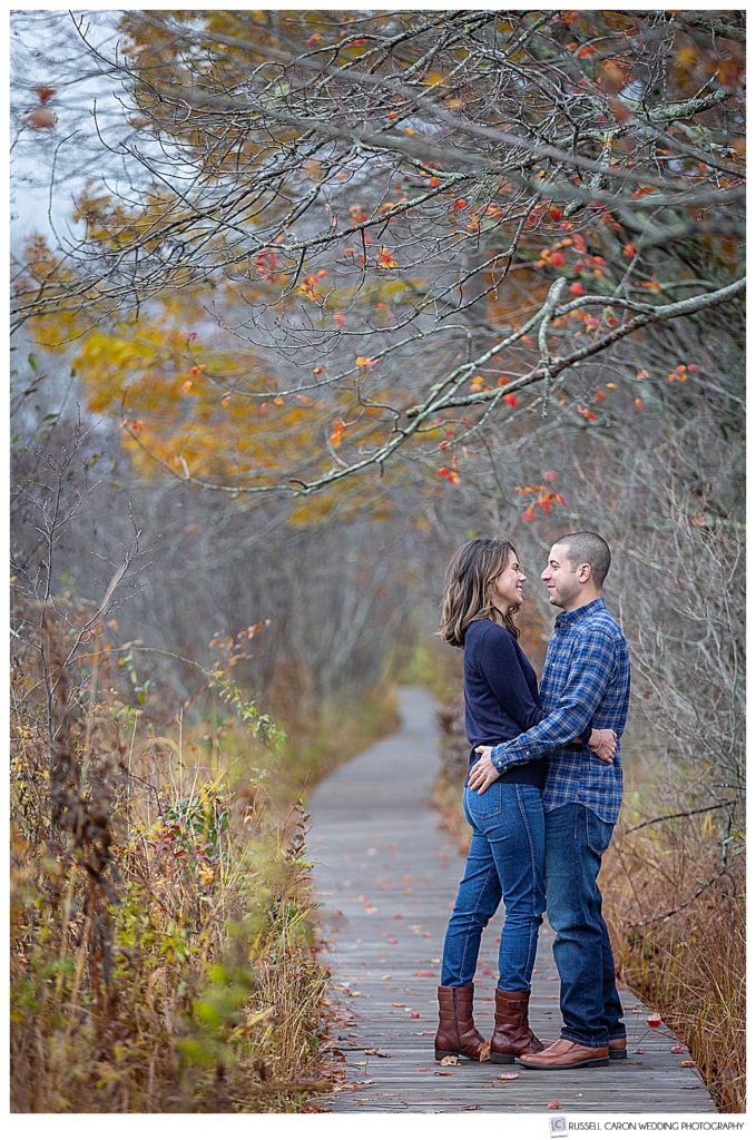 Mand and woman hugging each other on the boardwalk during their Cape Elizabeth engagement photo session