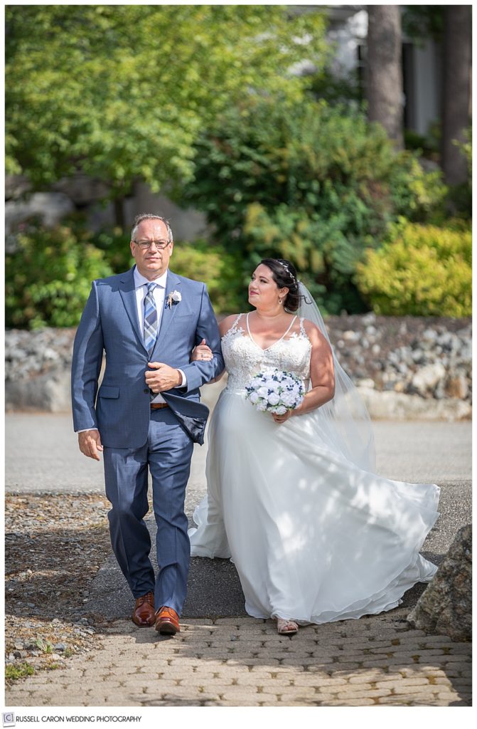 bride looking at her father as they walk down the aisle