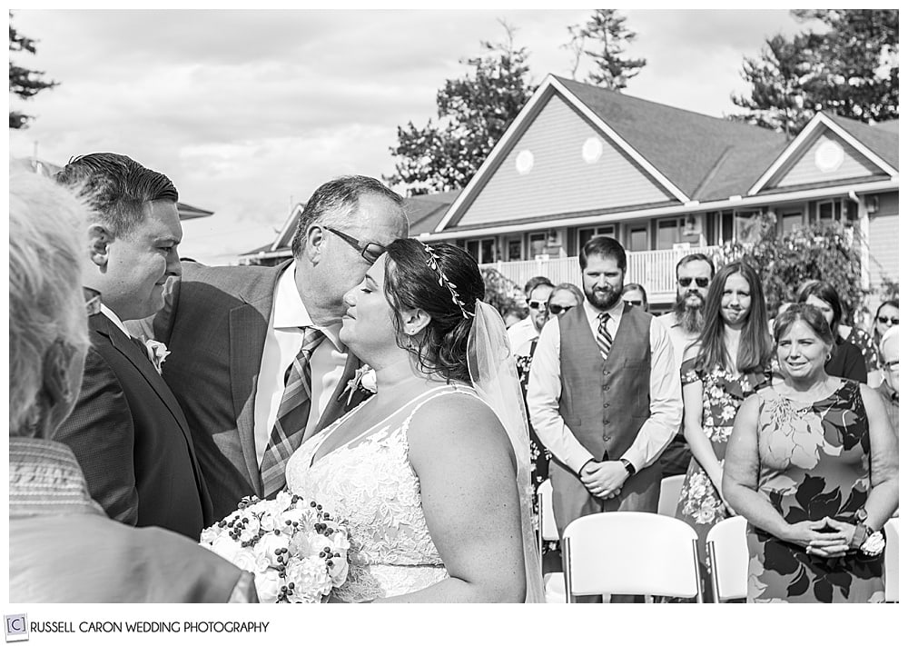 black and white photo of father kissing the bride at the altar