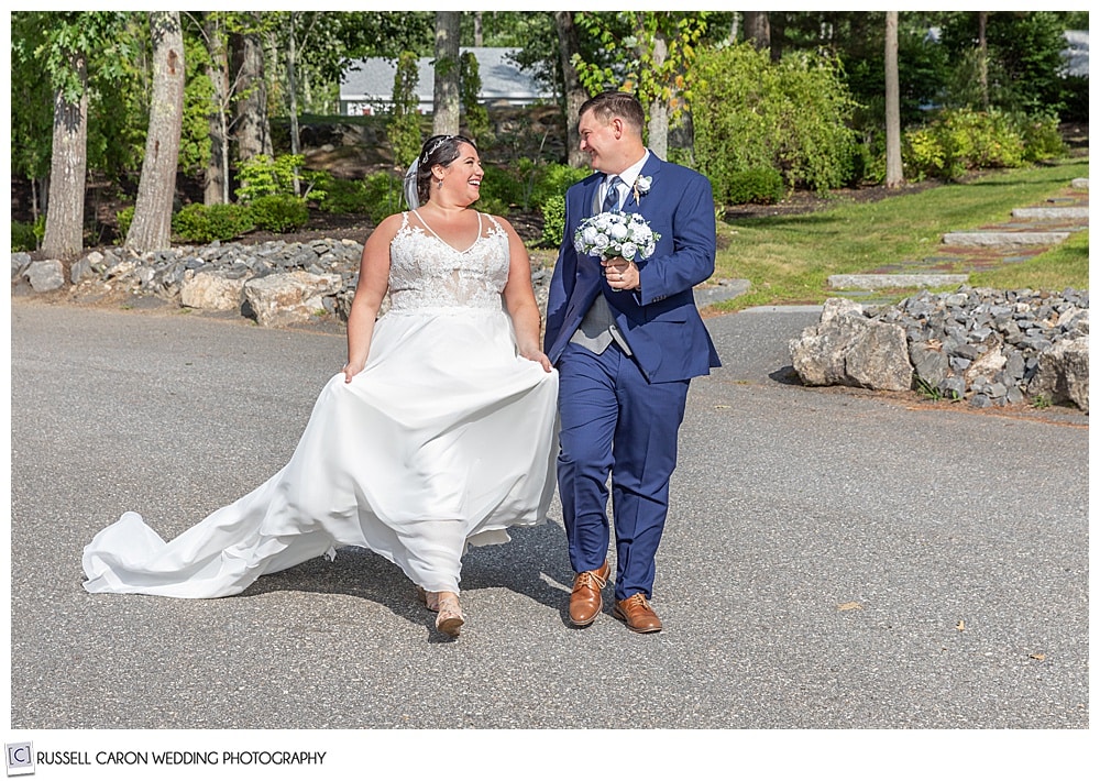 bride and groom walking together, groom is holding the bride's bouquet