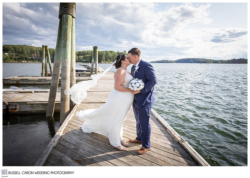 bride and groom kissing on a dock