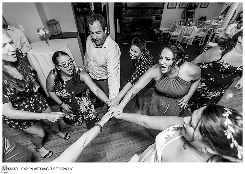 black and white photo of bride and friends with their hands together in the middle