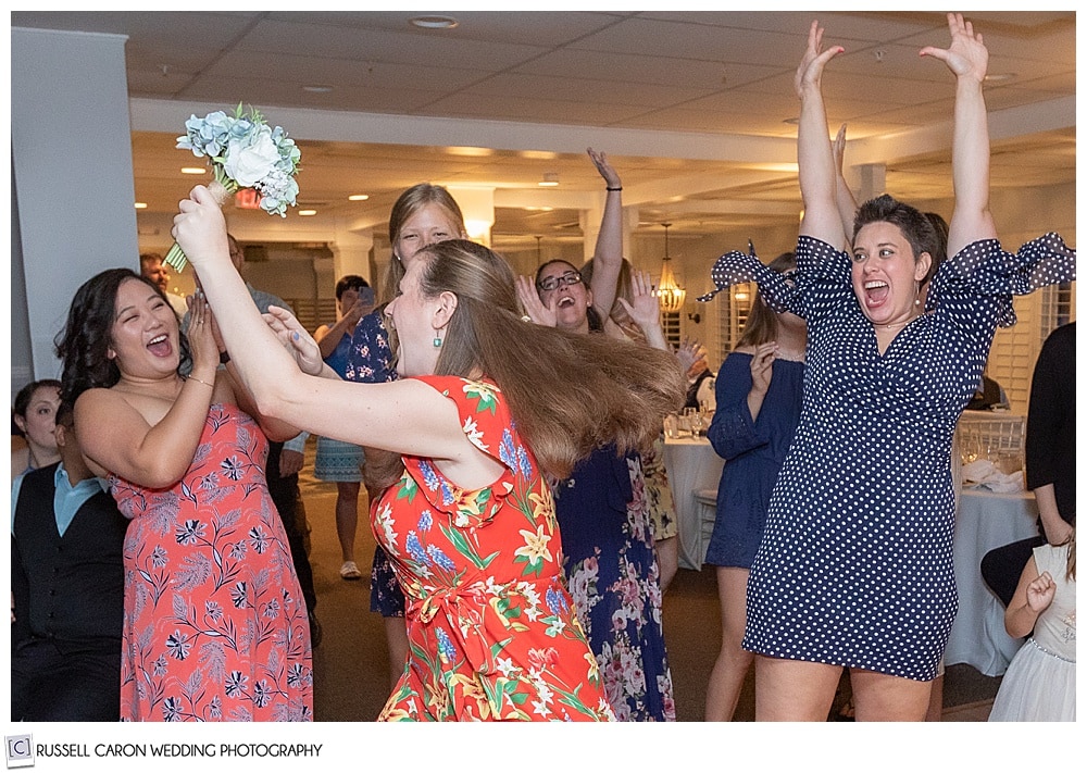 two wedding guests trying to get the bride's bouquet