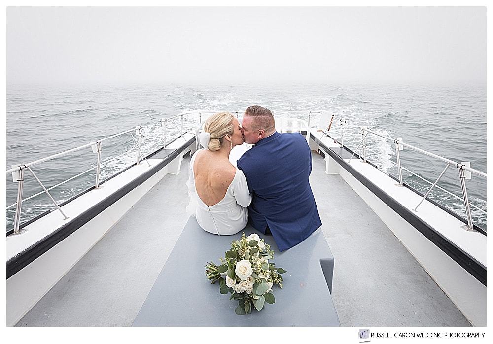 a bride and groom kissing on a boat during their foggy Newagen Seaside Inn wedding