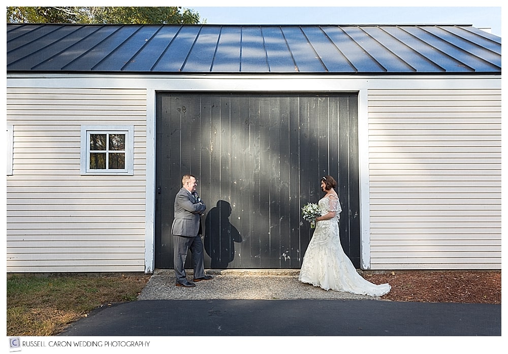 bride and groom in front of a white barn with black doors
