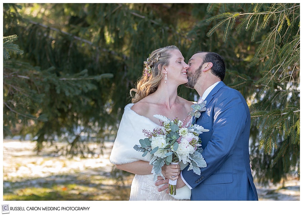 groom kissing bride on her cheek during their first look