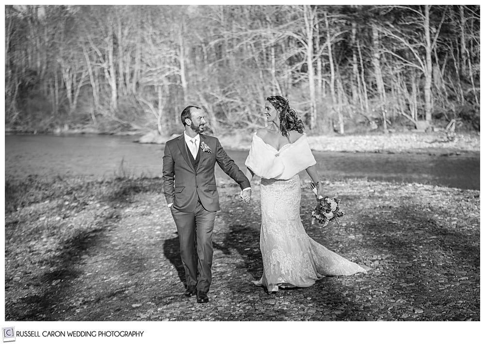 black and white photo of a bride and groom walking hand in hand