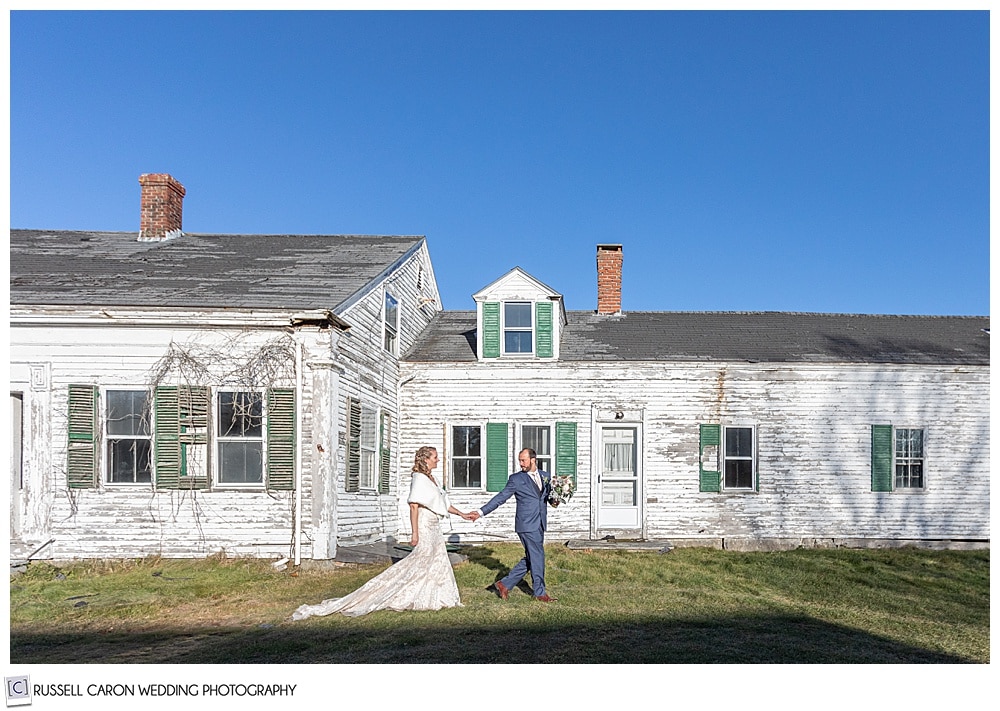 bride and groom walking in front of an old house