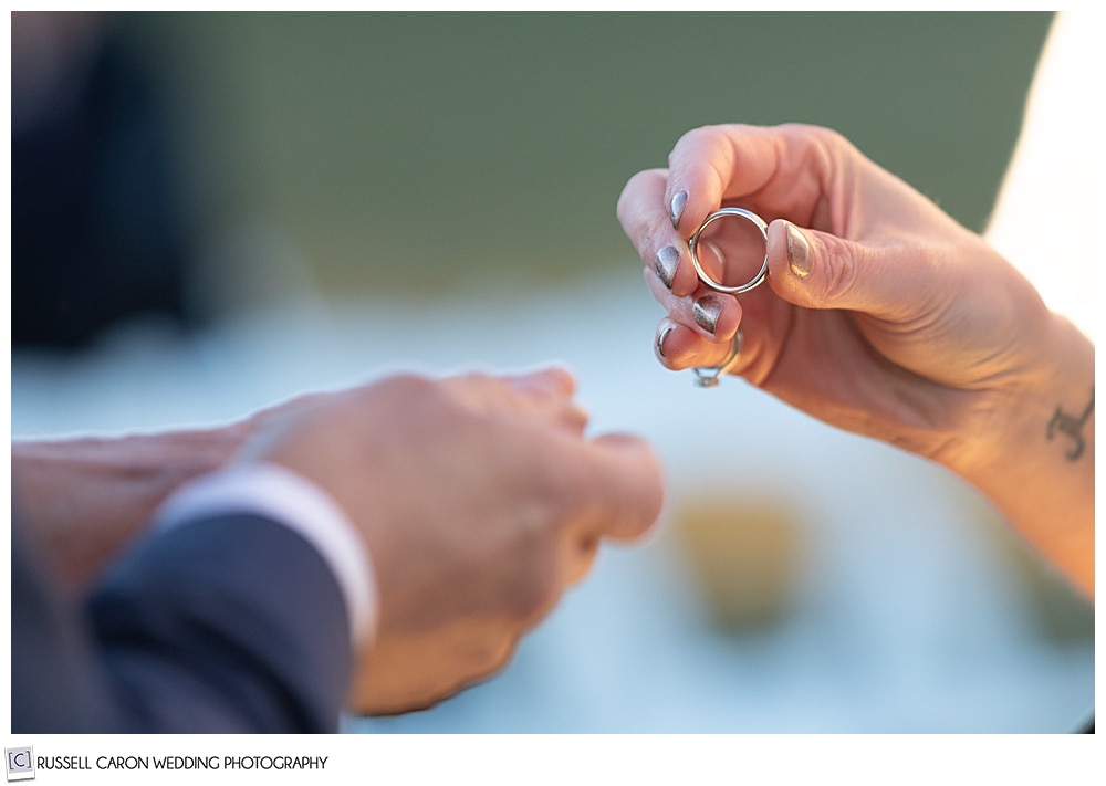 bride's fingers holding groom's wedding band