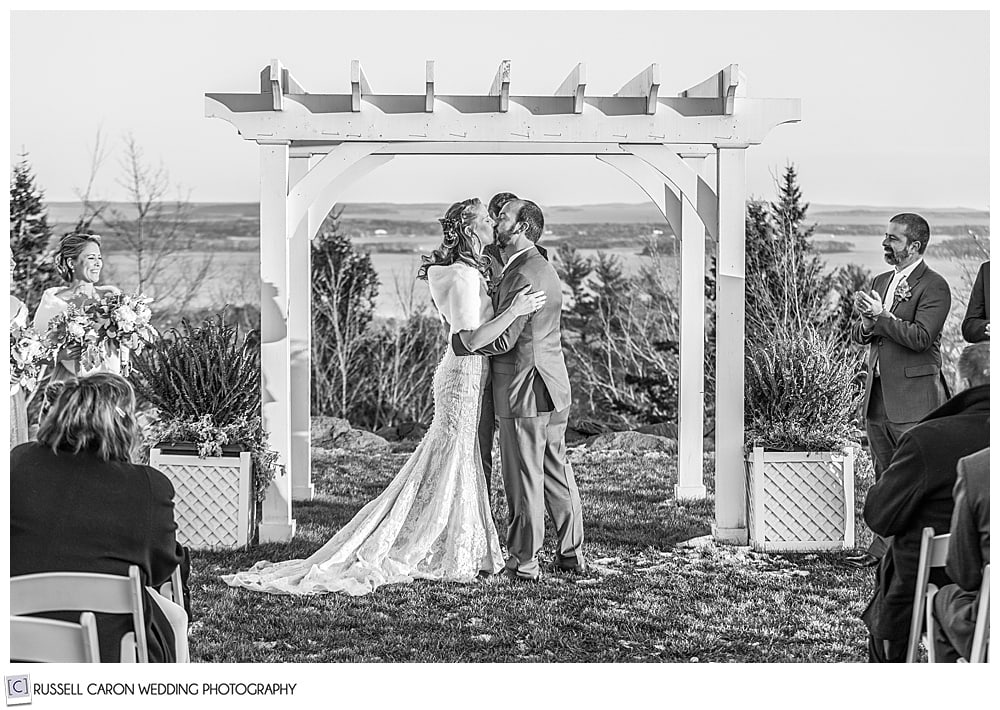 black and white photo of bride and groom's first kiss at their midcoast maine wedding ceremony 