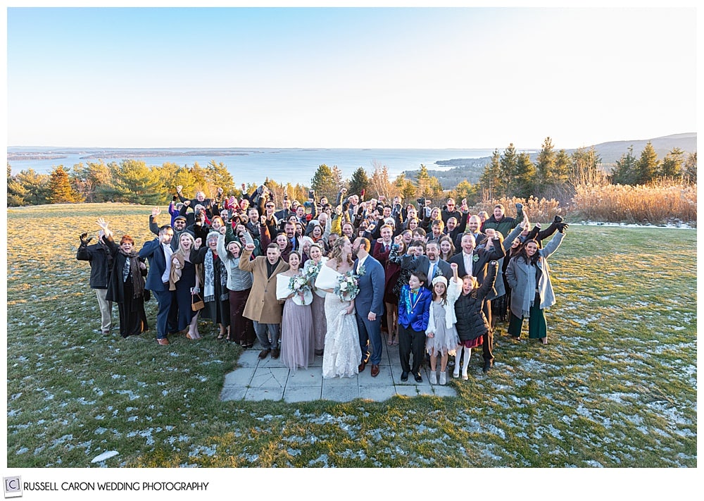 bride and groom surrounded by family and friends during their midcoast maine wedding at north port, maine