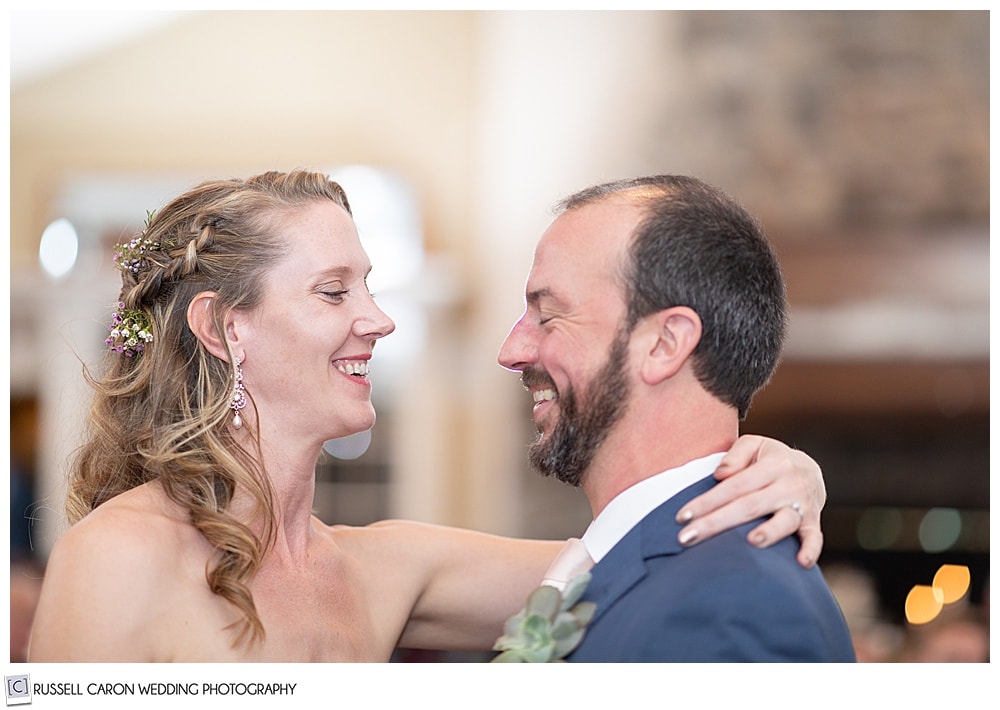 bride and groom smiling at each other during their first dance, at their midcoast maine wedding reception