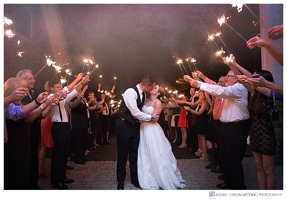 Bride and groom kissing during sparkler exits. Maine wedding photographers share tips on sparkler exits.
