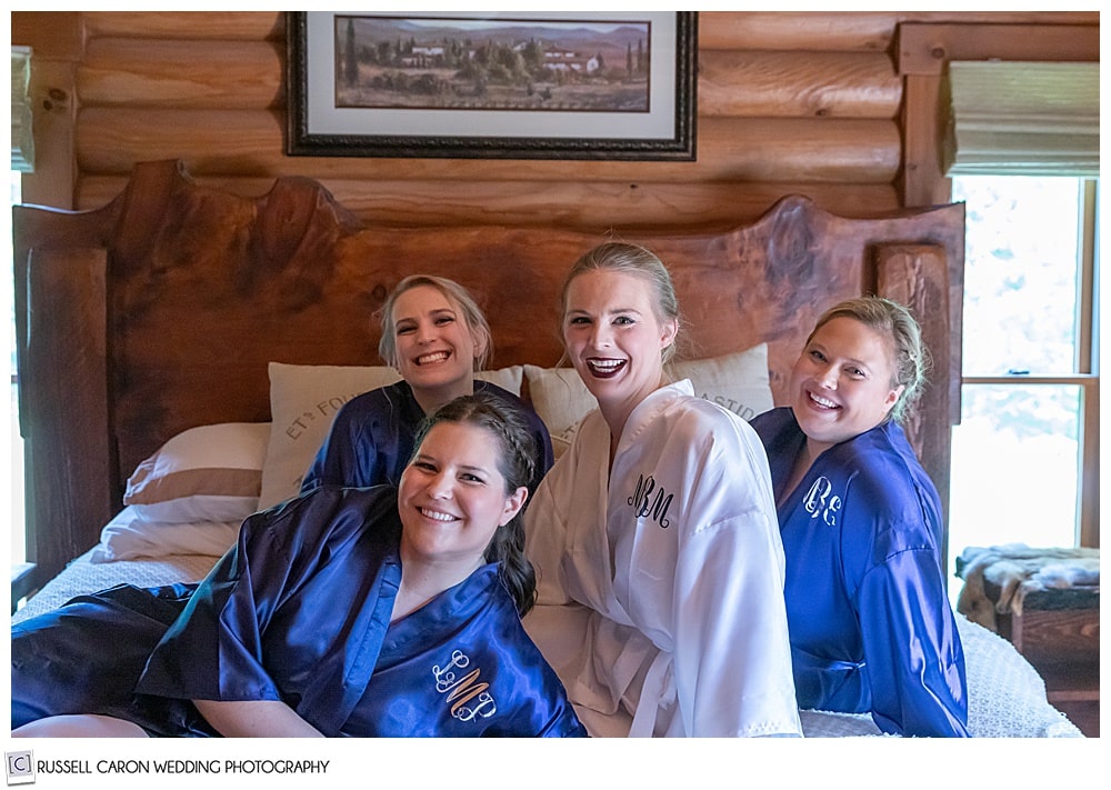 bride and bridesmaids on robes on a bed