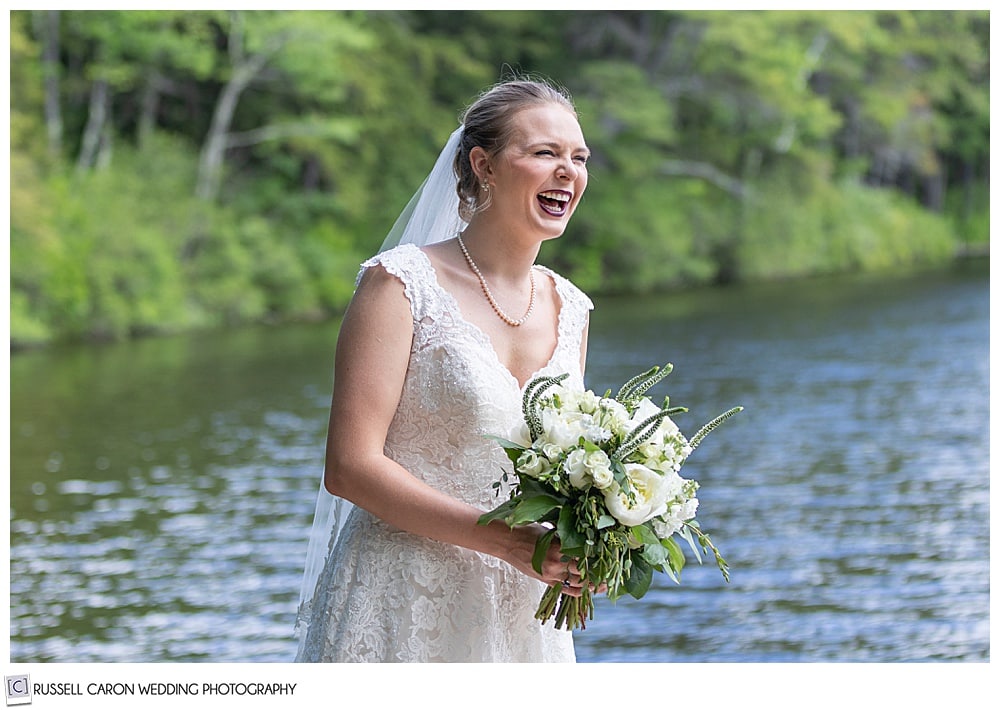 bride standing near a lake, smiling