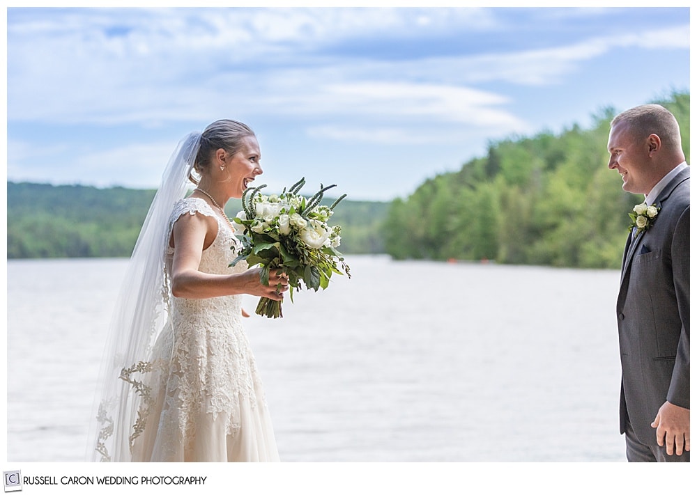 bride standing on a dock on a lake, smiling