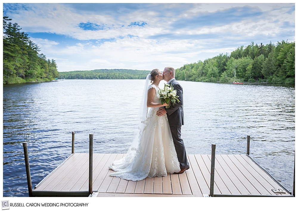 bride and groom kissing on a dock on a lake